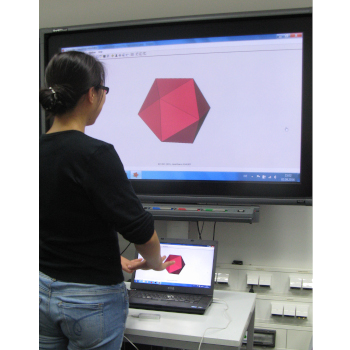 A student standing in front of a laptop, showing an icosahedron. She holds out her hands to interact with the leap motion controller box to control the program.